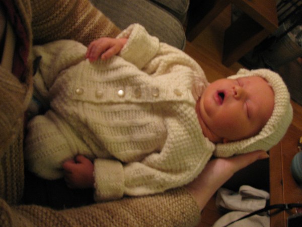 Naomi wearing a knitted romper and bonnet